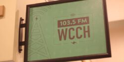 Photo of green sign attached to a wall that reads 103.5 FM WCCH at the Holyoke Community College radio station. Photo: J. Waits