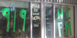 Photo of the outside of Williams College radio station WCFM. Large green writing on the station window reads "91.9 WCFM" and "tune in www.WCFM edu." Photo by J. Waits