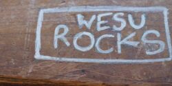 Photo of the phrase "WESU ROCKS" written in silver marker on a wooden table at the college radio station at Wesleyan University. Photo: J. Waits